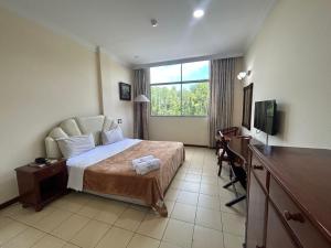 a hotel room with a bed and a television at Golden Village Hotel 