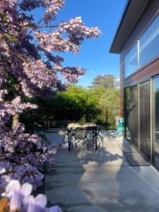 une terrasse avec une table et un arbre avec des fleurs roses dans l'établissement WARM Sunlit Sustainable north facing Studio, à Hawker