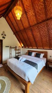 une chambre avec un grand lit avec un plafond en bois dans l'établissement Pondok Kanginan, à Plaga