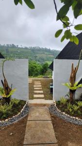un chemin en pierre menant à un bâtiment arboré dans l'établissement Pondok Kanginan, à Plaga