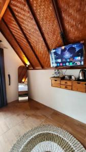 un salon avec une télévision à écran plat au mur dans l'établissement Pondok Kanginan, à Plaga