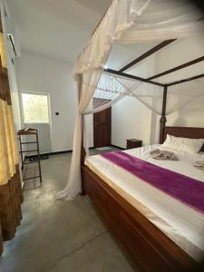 een slaapkamer met een hemelbed en een stoel bij Lyra Mirissa in Mirissa