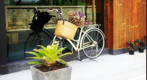 een fiets geparkeerd naast een gebouw met bloemen in een mand bij Klim Hotel in Buriram