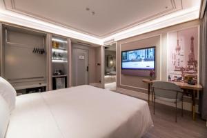 上海上海徐汇日月光美居酒店的一间卧室，里面有一张床、一张桌子和一台电视。