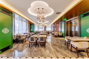 a restaurant with tables and chairs and a chandelier at Mercure Huhhot Economic Zone in Hohhot