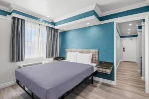 un lit dans une chambre avec un mur bleu dans l'établissement Rodeway Inn Commerce - Los Angeles, à Commerce