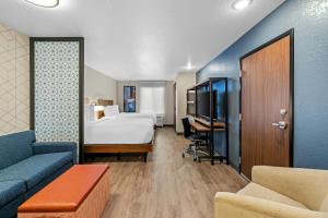 een hotelkamer met een bed, een bank en een tv bij Everhome Suites Rochester Greece in Rochester