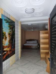 ein Schlafzimmer mit einem Bett und einem Gemälde an der Wand in der Unterkunft Prof's Villa in Kumasi