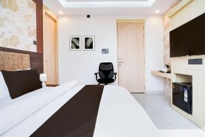 ein Schlafzimmer mit einem Bett und einem schwarzen Stuhl in der Unterkunft Townhouse Oak Ram Lala Mandir Kanpur Formerly Hotel Sun Rise in Kaliānpur