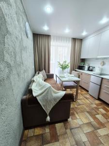 a kitchen and living room with a couch and a table at Отдых перед и до вылета самолёта in Astana