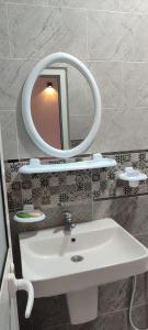 een badkamer met een witte wastafel en een spiegel bij Appartement Naim in Tozeur +6 foto's