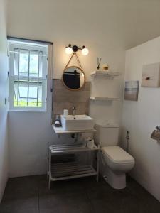 une salle de bain avec toilettes, lavabo et fenêtre dans l'établissement El-Sangha Studio 2mina pieds de la plage de baie du cap, à Ruisseau Créole