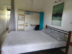 une chambre avec un grand lit blanc dans une pièce dans l'établissement El-Sangha Studio 2mina pieds de la plage de baie du cap, à Ruisseau Créole