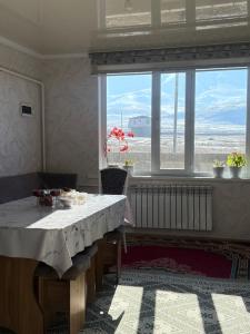 een eetkamer met een tafel en een groot raam bij Gulbara Guest House in Toguz-Bulak