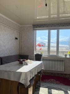 een eetkamer met een tafel en een groot raam bij Gulbara Guest House in Toguz-Bulak