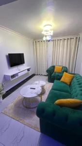 een woonkamer met een groene bank en een tafel bij Infinite Stays in Thika