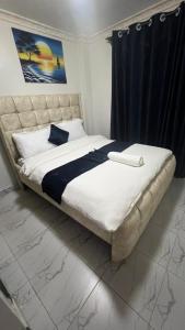 een slaapkamer met een groot bed en een zwart gordijn bij Infinite Stays in Thika +2 foto's