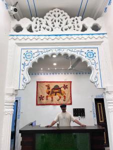 a man standing at a counter in a room with a painting at Riga House in Udaipur