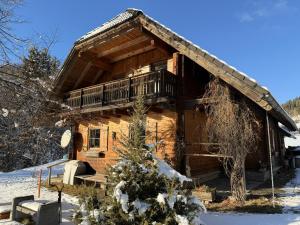 une cabane en rondins dans la neige avec un balcon dans l'établissement KlauBär - Hütte, à Steirisch Laßnitz