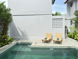 two chairs next to a swimming pool in a house at Manik Tropicana Loft in Canggu