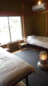 zwei Betten in einem Zimmer mit Fenster in der Unterkunft Cosmos Guesthouse Iya Valley in Akano