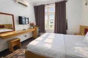 ein Schlafzimmer mit einem Bett, einem Spiegel und einem Fernseher in der Unterkunft Minh Hà Hotel Hồ Chí Minh in Ho-Chi-Minh-Stadt