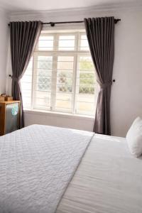 ein Schlafzimmer mit einem weißen Bett und einem Fenster in der Unterkunft Minh Hà Hotel Hồ Chí Minh in Ho-Chi-Minh-Stadt