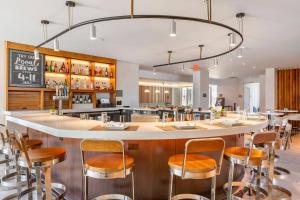 a restaurant with a large bar with stools at Cambria Hotel LAX in El Segundo