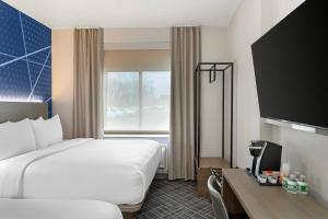ein Hotelzimmer mit einem Bett und einem Schreibtisch mit einem Fernseher in der Unterkunft Comfort Inn in Staten Island + 48 Fotos