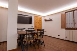 a dining room with a table and chairs and a flat screen tv at LAB Cottage in Madonna di Campiglio