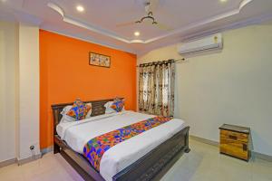 a bedroom with a bed with an orange wall at FabHotel Sri Balaji Grand in Hyderabad