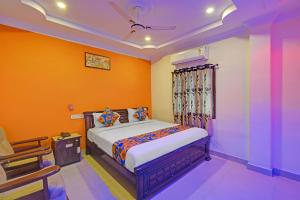 a bedroom with a bed with an orange wall at FabHotel Sri Balaji Grand in Hyderabad