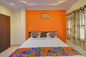 a bedroom with a bed with an orange wall at FabHotel Sri Balaji Grand in Hyderabad