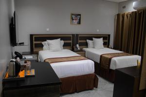 ein Hotelzimmer mit zwei Betten und einem Schreibtisch in der Unterkunft LENNON QUALITY Hotel in Umtali