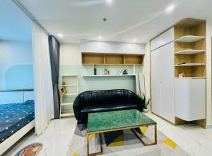 a living room with a black leather couch and a bed at Alex Vinhomes Grand in Gò Công