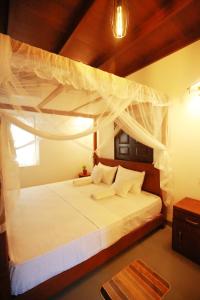 a bedroom with a white bed with a canopy at Kandy House Hiriketiya in Dickwella