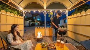 un uomo e una donna che cucinano cibo in un gazebo di GaPyeong Lucerne kids Spa Pension a Gapyeong