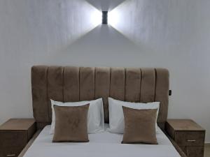 een bed met twee kussens en een licht erboven bij Baya Residentie in Temara