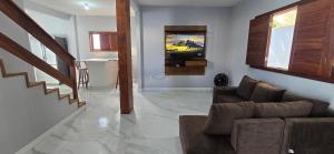 a living room with a couch and a television at Casa Temporada Conchinha do Mar in São Mateus