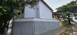 a white house with a fence in front of a building at Casa Temporada Conchinha do Mar in São Mateus