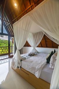 una camera da letto con letto a baldacchino con tende bianche di The Pyramid Ubud River Villas a Gianyar