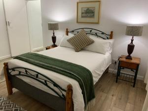 a bedroom with a bed with a green blanket and two lamps at Armadale Cottage in Lidgetton