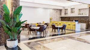 een restaurant met tafels en stoelen en een plant bij Enrich Grand Hotel in Bangkok