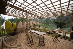 a deck with surfboards and a table and a chair at Lagom Village-Glamping Site- Đồng Đò lake view in Hanoi +39 photos
