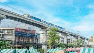 een trein op een brug over een stad met tenten bij Enrich Grand Hotel in Bangkok
