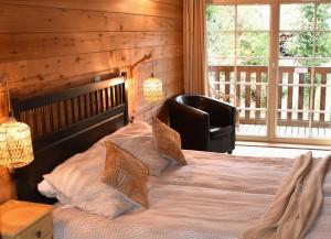 a bedroom with a bed with a chair and a window at Trésor en Bois Chambres d'Hôtes in Autoire