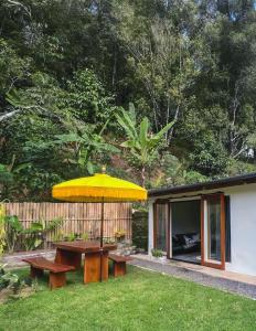 un tavolo da picnic con un ombrellone giallo in un cortile di Little Munduk, full private villa a Munduk