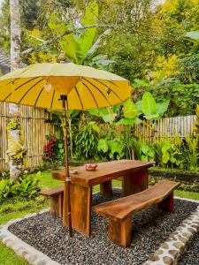 a picnic table with a yellow umbrella and a bench at Little Munduk, full private villa in Munduk