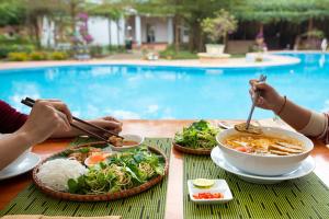 zwei Personen sitzen an einem Tisch mit einer Schüssel Essen in der Unterkunft Chay Lap Farmstay Phong Nha in Ðá Lòn