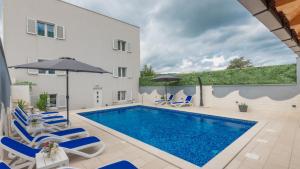 a pool with chairs and umbrellas next to a building at Star Hill - Makarska by Villas Guide in Slivno